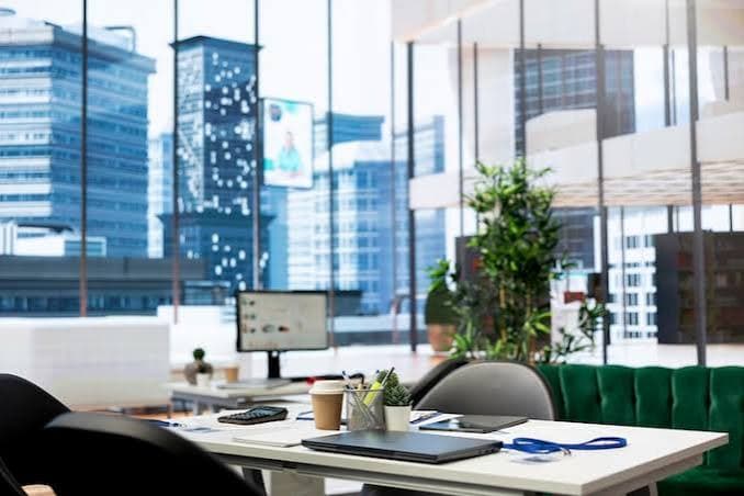 Modern open office with desks, plants and floor-to-ceiling windows over the city